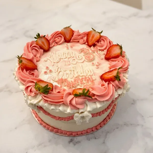 Pink rosette cake with fresh strawberries and Happy Birthday piping
