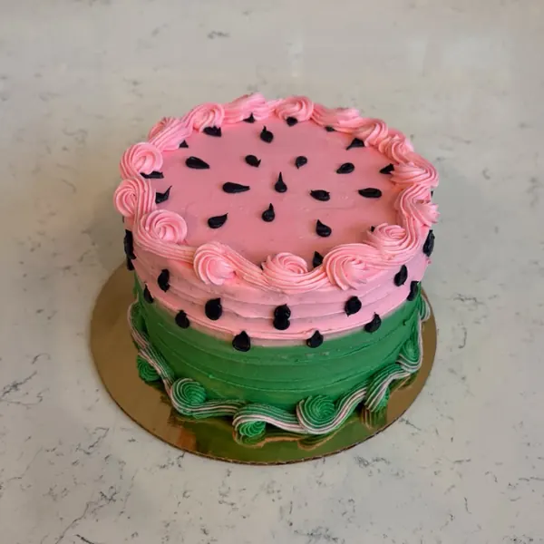 Watermelon cake with pink rosettes, green sides and chocolate seeds